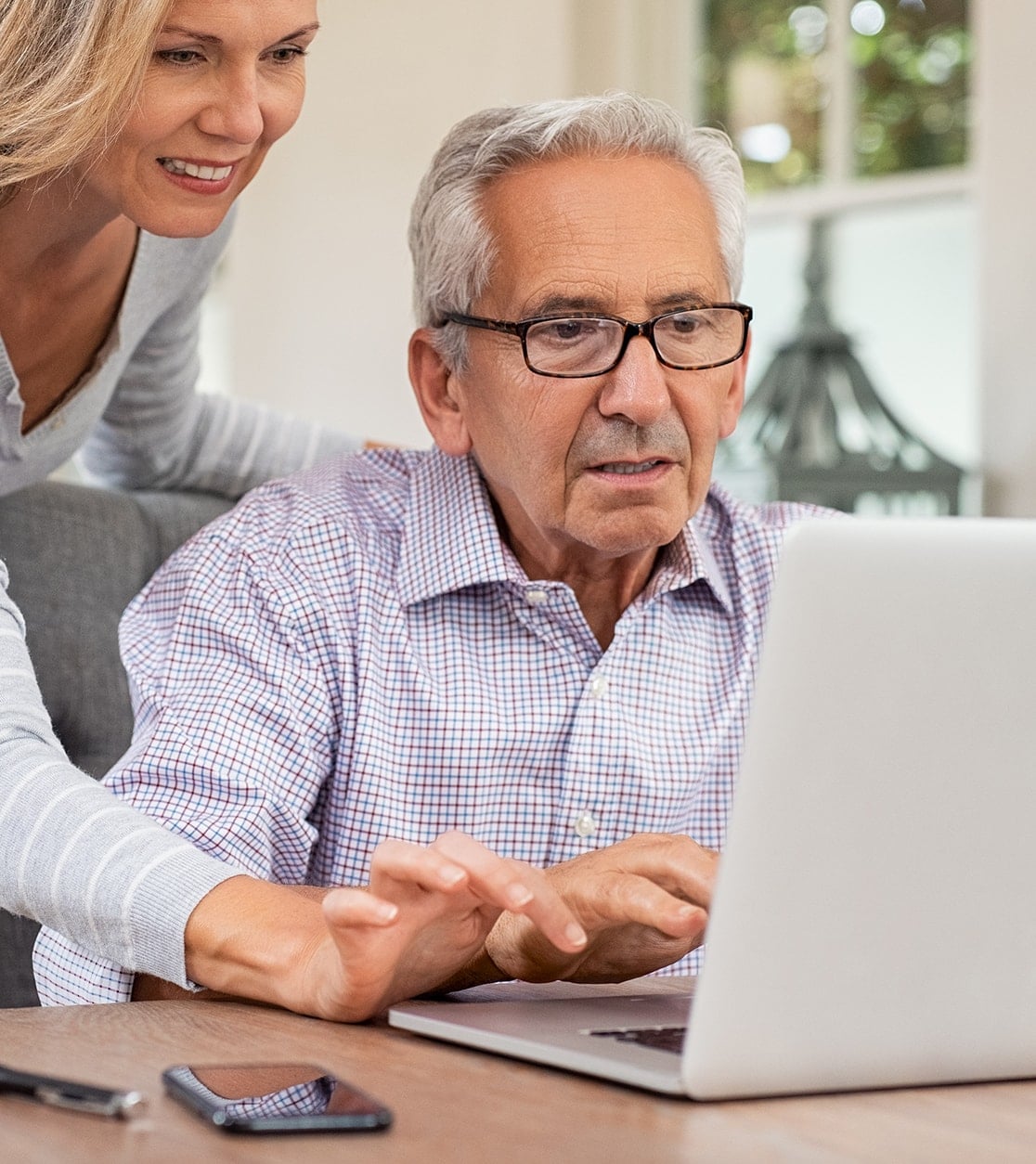woman helping elder man with his laptop