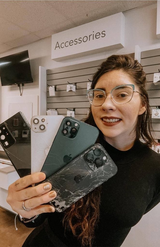 woman smiling while holding broken phones